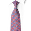 Knotted red silk tie with repeating blue circles, pale outlines and crystal rhinestone accents against a white shirt.