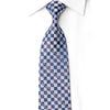 A patterned necktie with a blue, white, and gray geometric design, styled on a white collared dress shirt against a white background.
